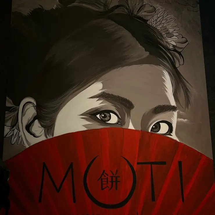 Мурал в зале Moti: девушка прячет лицо за красным веером с надписью MOTI